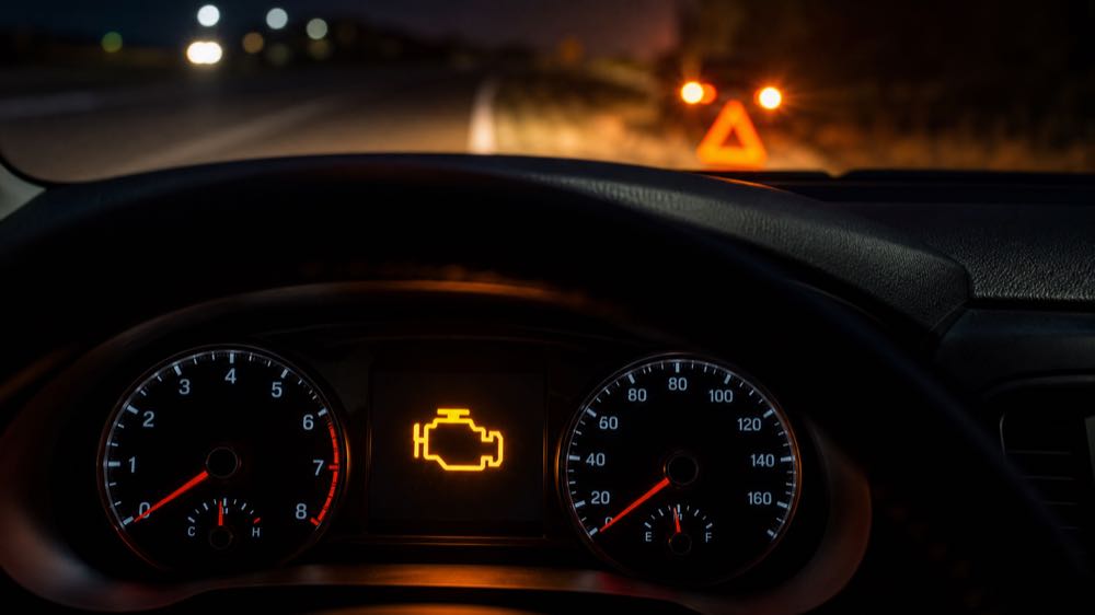 Flashing check engine light glowing on a dashboard while a car is safely pulled over