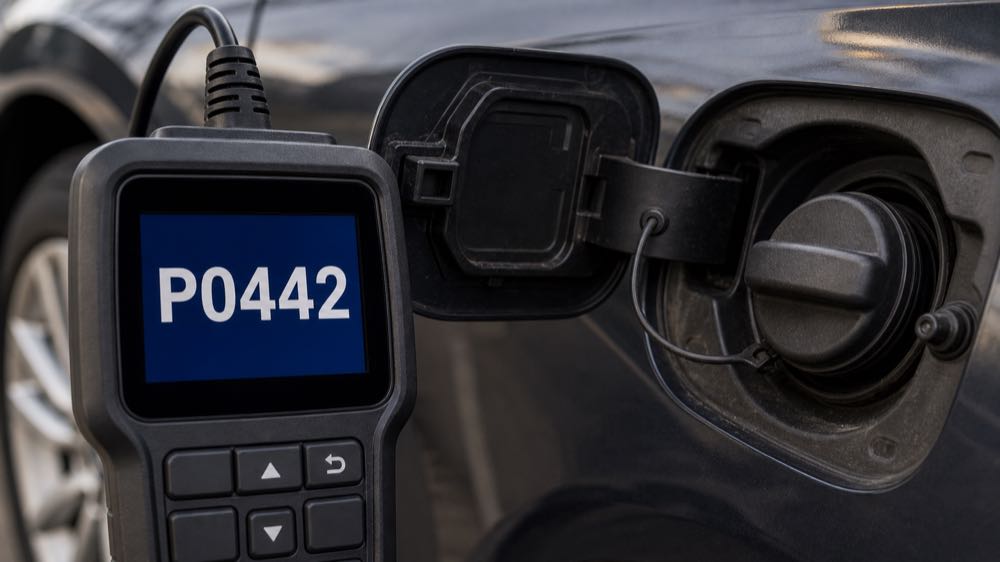 OBD2 scanner showing P0442 code near a vehicle gas cap
